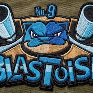 May include: Embroidered patch featuring a blue Blastoise design with two cannons and the text "BLASTOISE" in a stylized font. The patch includes the number "No. 9" at the top. The design is set against a tan and black background.