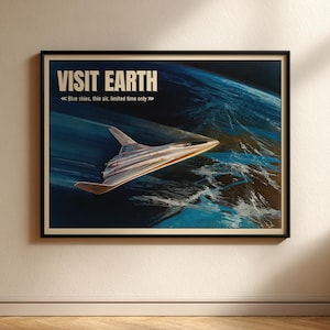 May include: A framed poster with the words "VISIT EARTH" in white capital letters. The poster features a futuristic silver and orange spacecraft flying above a blue and white planet. The text "Blue skies, thin air, limited time only" is also included.