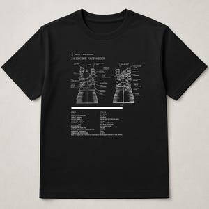May include: Black t-shirt featuring a white diagram of a J-2 engine with the text "J-2 ENGINE FACT SHEET". The diagram includes detailed technical specifications and schematics of the engine's components.