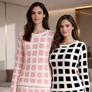 May include: Two women wearing matching crochet sweaters. One sweater is white with pink squares, the other is white with black squares. Both sweaters have long sleeves and a crew neck. The outfits appear to be a matching set.