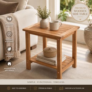 May include: A square wooden side table with a slatted top and a lower shelf. The table features four straight legs and a natural wood finish. On the top surface sits a small potted plant and a ribbed mug. A woven box and two books rest on the lower shelf.