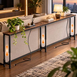 May include: A long, narrow console table with a rustic brown wood-grain surface and a black metal frame. The table features adjustable height legs, indicated by orange arrows, and includes built-in power outlets on the top surface.