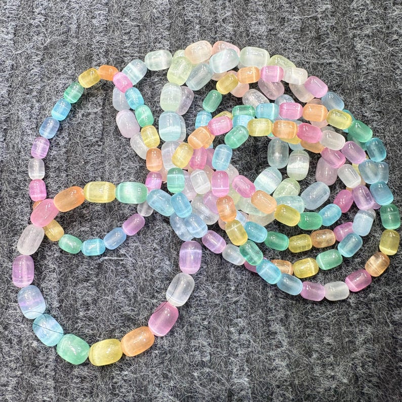 May include: A collection of colorful, translucent gemstone beads in shades of pink, orange, yellow, green, and blue. The beads are strung together, creating a necklace or bracelet.