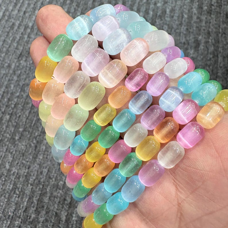 May include: A collection of colorful, oval-shaped beads in a variety of pastel colors, including yellow, green, pink, and blue. The beads are strung together, creating a vibrant and eye-catching display. The beads are approximately 0.5 inches in length.