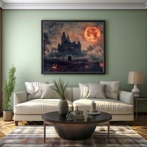 May include: A framed Halloween-themed artwork depicts a spooky castle under a full orange moon. The scene includes jack-o'-lanterns, trees, and a graveyard, creating a dark and atmospheric ambiance. The artwork is displayed above a white sofa in a living room.