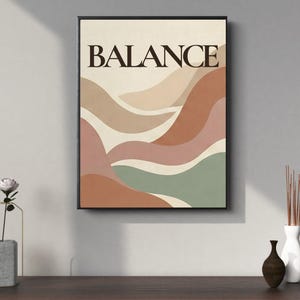 Puede incluir: Una impresión artística enmarcada con la palabra "BALANCE" en una fuente oscura y audaz. La obra de arte presenta formas abstractas en capas en tonos beige, marrón, rosa y verde. La impresión se muestra sobre una superficie de madera oscura.