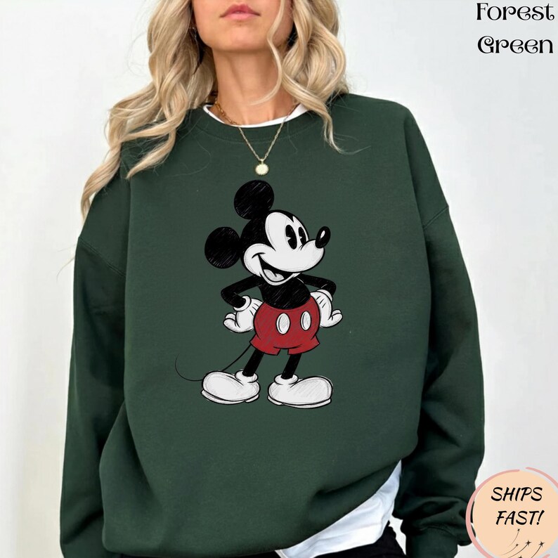 May include: Forest green sweatshirt featuring a classic Mickey Mouse graphic. The cartoon character is depicted in black, white, and red. The sweatshirt has a crew neck and long sleeves. The text "Forest Green" is printed on the top right.