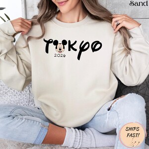 May include: A white ceramic mug with a black handle and the text "But First, Coffee" in a bold, black font. The mug is set against a blurred background, suggesting a cozy setting. The mug appears to be approximately 4 inches tall.