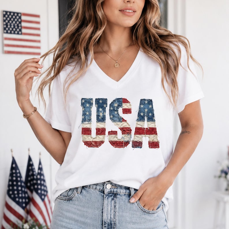 Op de afbeelding: Wit V-hals T-shirt met het woord "USA" in een versleten Amerikaans vlagontwerp. De letters zijn blauw met witte sterren en rood-witte strepen. Het shirt is gemaakt van een zacht materiaal.