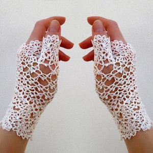 May include: A pair of white crocheted fingerless gloves with a delicate floral pattern.