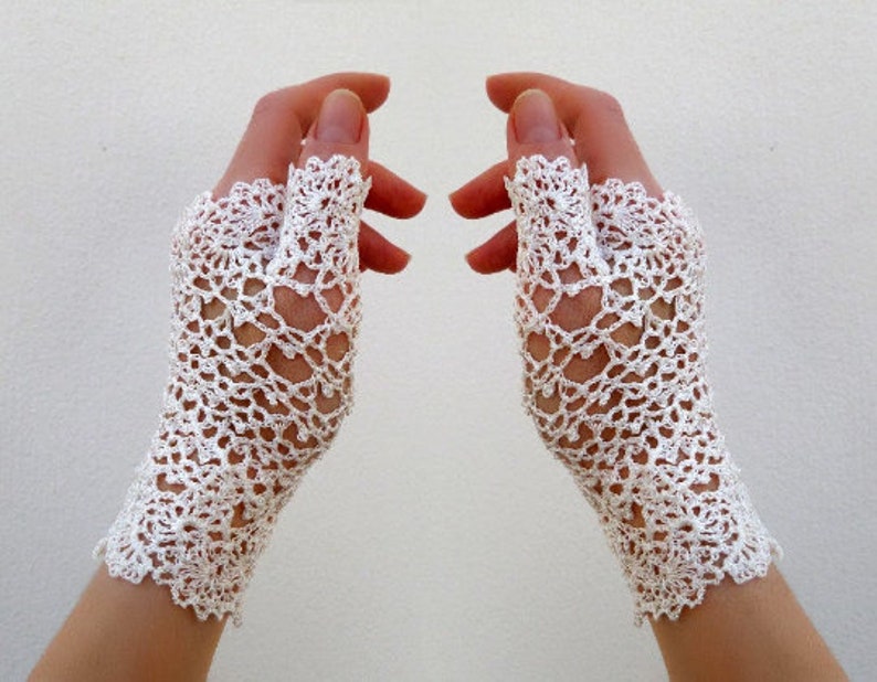 May include: A pair of white crocheted fingerless gloves with a delicate floral pattern.