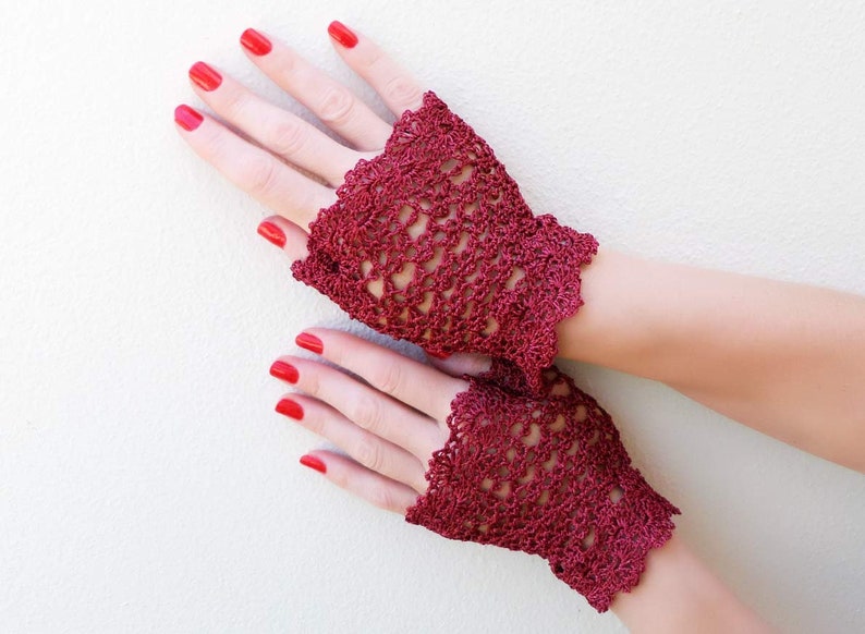 May include: A pair of burgundy crochet fingerless gloves with a delicate lace pattern.