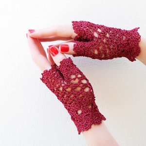 May include: A pair of burgundy crochet fingerless gloves with a lacy design.