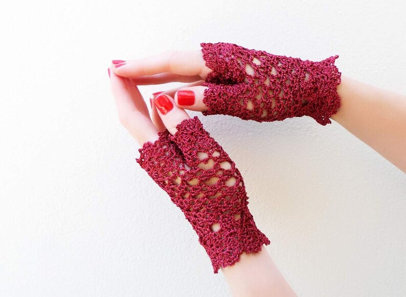 May include: A pair of burgundy crochet fingerless gloves with a lacy design.