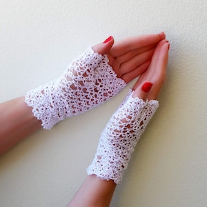 May include: A pair of white crocheted fingerless gloves with a delicate lace pattern.