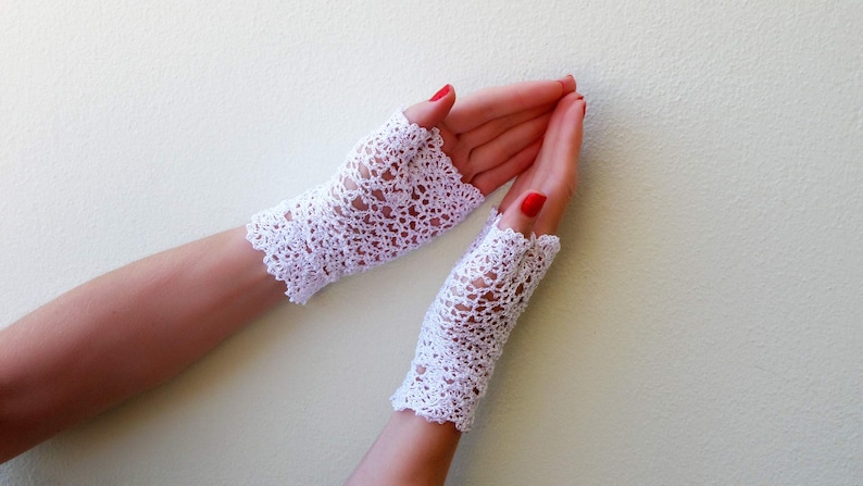 May include: A pair of white crocheted fingerless gloves with a delicate lace pattern.