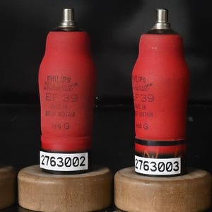 May include: Four red Philips Miniwatt EF39 vacuum tubes with metal tops, each mounted on a circular wooden base with a white serial number label. Four rectangular cardboard boxes are included, each labeled with Philips Miniwatt EF39 specifications.