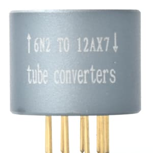 May include: A cylindrical gray vacuum tube adapter with gold-colored pins at the base. The side of the component features white printed text that reads 6N2 TO 12AX7 with arrows and the words tube converters centered below the model numbers.