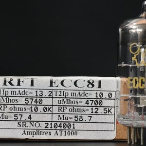 May include: A clear glass vacuum tube labelled ECC81 with internal metal components, positioned next to a rectangular cardboard box. The box features a white label with black text including RFT ECC81, technical specifications, and Amplitrex AT1000.