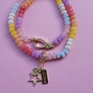 May include: A multi-colored beaded bracelet with a gold charm featuring a star and the word "LOVE". The beads are in shades of pink, yellow, blue, and purple.