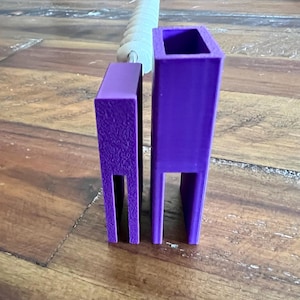May include: Two purple, rectangular, 3D-printed objects with open bottoms and tops. One has a textured surface, the other is smooth. A white, ridged object is partially visible in the background.