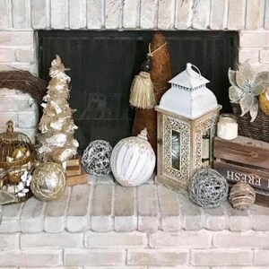Pu&ograve; includere: Un camino in mattoni bianchi decorato per le festivit&agrave; con una variet&agrave; di ornamenti, tra cui una gabbia per uccelli, una lanterna e una cassa di legno con il testo "Farm Fresh".