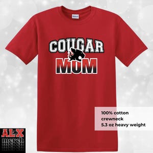 May include: Red crewneck t-shirt with the text "COUGAR MOM" in white and black lettering, featuring a cougar graphic. The shirt is made of 100% cotton and is 5.3 oz heavy weight.