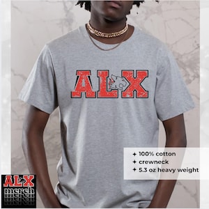 May include: A light gray crewneck t-shirt with the letters "ALX" in red block letters with a distressed effect. The "L" is replaced with a cougar graphic. The shirt is 100% cotton and 5.3 oz heavy weight.