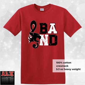 May include: Red crewneck t-shirt with a black and white graphic that says "BAND". The design includes a treble clef, a panther head, and flames. The shirt is made of 100% cotton and is 5.3 oz heavy weight.