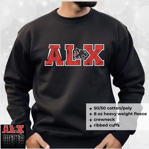 May include: Black crewneck sweatshirt with the red letters "ALX" and a panther logo. The sweatshirt has ribbed cuffs and is made of 50/50 cotton/poly 8 oz heavy weight fleece. The text "ALX merch" is in the lower left corner.