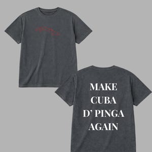 May include: Two charcoal gray t-shirts. The front shirt has a red outline of Cuba. The back shirt has the text "MAKE CUBA D' PINGA AGAIN" in white. The shirts are short-sleeved and have a vintage, washed look.