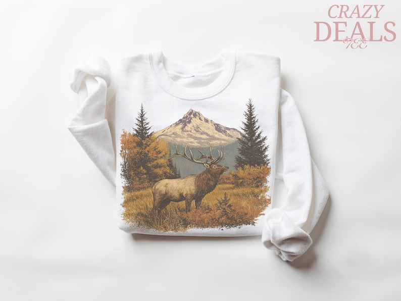 May include: White sweatshirt with a detailed illustration of an elk in a mountain landscape. The design includes a mountain, trees, and autumn foliage. The text "CRAZY DEALS" is in the upper right corner.