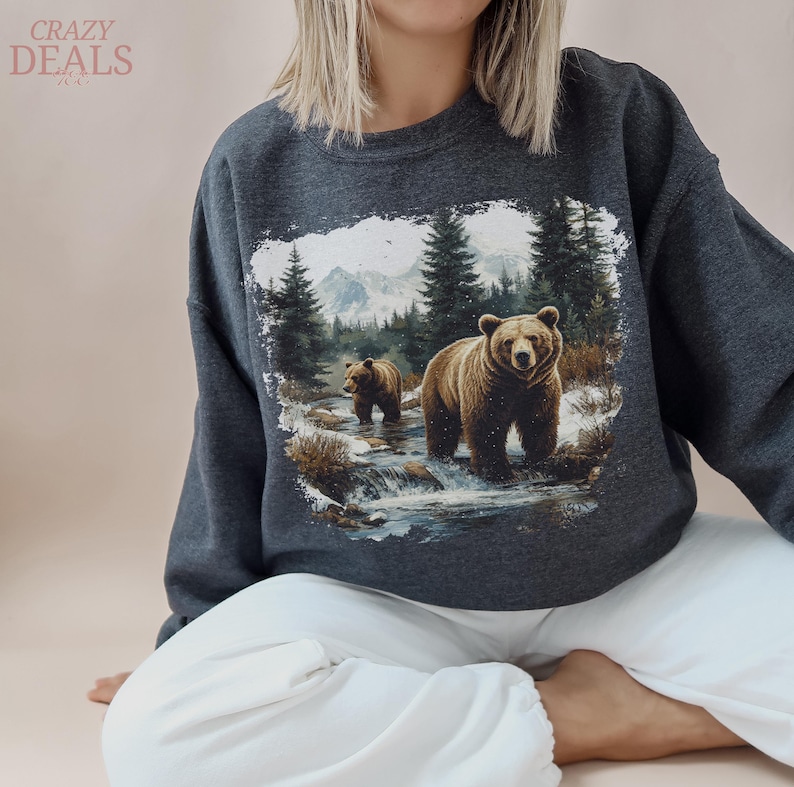 May include: Dark gray sweatshirt featuring a detailed graphic of two brown bears in a snowy forest scene with a river and mountains. The sweatshirt has the text "CRAZY DEALS" in the upper left corner.