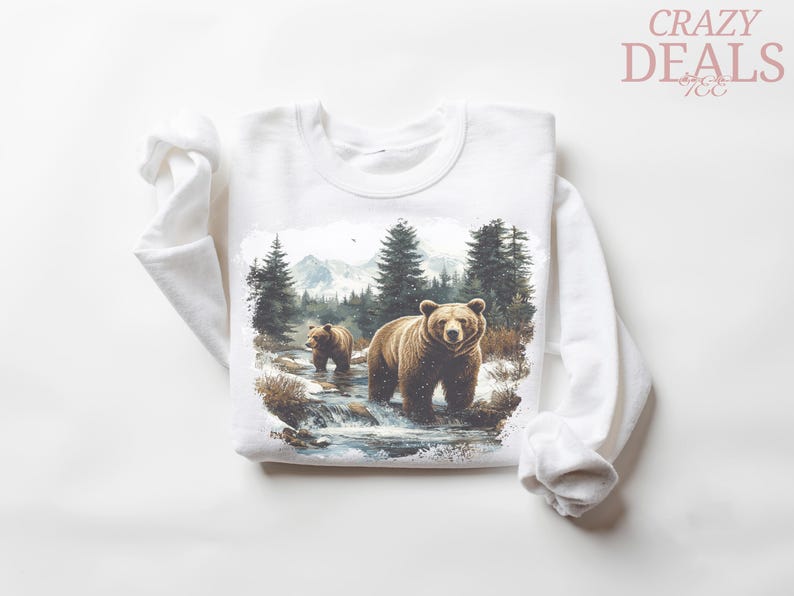 May include: White long-sleeved sweatshirt featuring a watercolor illustration of two brown bears in a forest stream. The design includes trees, mountains, and the text "CRAZY DEALS".