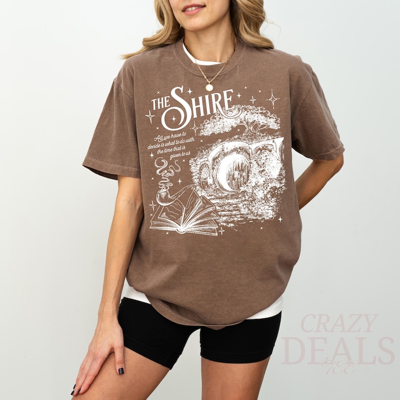 May include: Brown t-shirt with the text "THE SHIRE" and a graphic of a book, pipe, and moon. The shirt also has the quote "All you have to decide is what to do with the time that is given to us."
