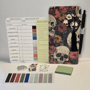Peut inclure: Un ensemble de papeterie comprenant un carnet avec un motif de crâne et de fleurs, un stylo noir, des notes autocollantes, des cartes d'annotation et des marque-pages colorés. L'ensemble comprend des autocollants avec le texte "I'm a Dark Romance Addict" et "Dark Haunting Book Club".