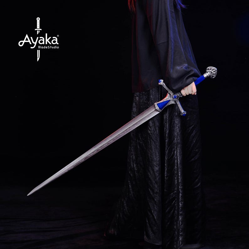 May include: A long, silver sword with a blue handle and crossguard. The sword has a detailed design on the hilt and crossguard. The blade is long and sharp, and the sword is held against a black background. The Ayaka BladeStudio logo is in the upper left corner.
