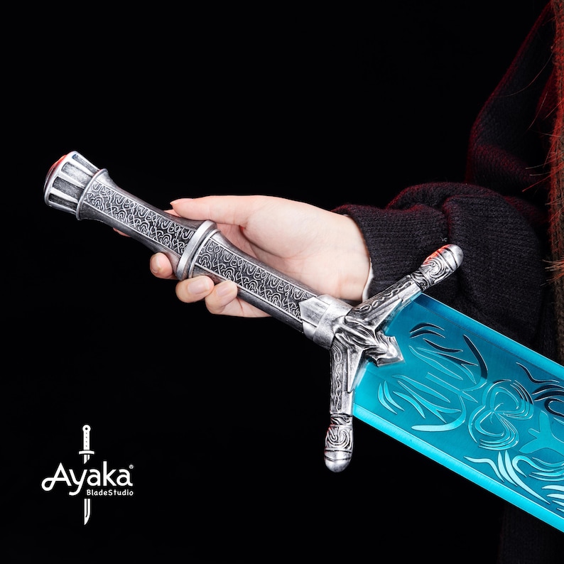 May include: A detailed fantasy sword with a silver handle and a translucent blue blade. The handle features intricate engravings and a red accent at the pommel. The blade has a decorative etched design. The sword is held against a dark background.