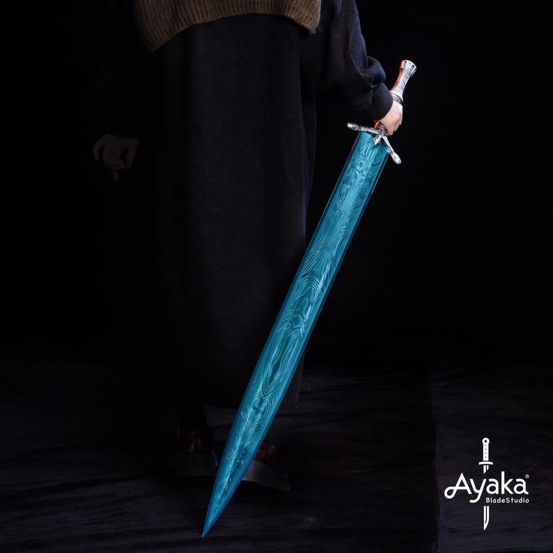 May include: A long, blue sword with a patterned blade is held against a dark background. The sword has a silver hilt and a red accent near the handle. The blade has a textured, wave-like pattern. The logo "Ayaka BladeStudio" is in the bottom right corner.