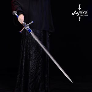 May include: A long, silver sword with a blue and silver hilt. The sword has a cross-shaped guard and a detailed design on the blade. The hilt features a blue gem and ornate silver accents. The sword is held against a dark background.