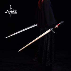 May include: Two swords are displayed against a black background. One sword has a silver blade and a red handle. The other sword has a wooden blade and a silver handle. The logo "Ayaka BladeStudio" is in the upper left corner.