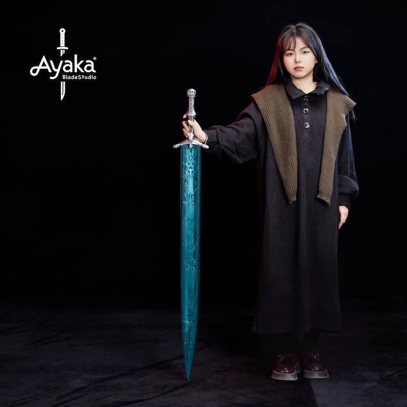 May include: A long, ornate sword with a teal blade and silver hilt. The blade features intricate engraved designs. The sword is held by a person wearing a black coat and a brown scarf. The logo "Ayaka BladeStudio" is in the upper left corner.