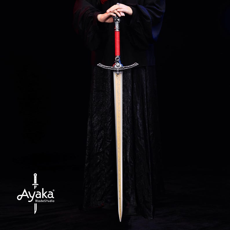 May include: A long sword with a silver hilt, red wrapped handle, and a light-colored blade. The sword is held against a black background. The sword's hilt has intricate details. The blade has a wood grain pattern. The sword is a prop or decorative item.