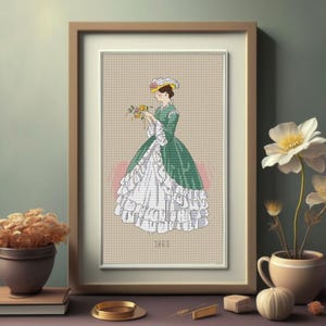 Peut inclure: Image d'une broderie au point de croix encadrée représentant une femme en robe verte et blanche tenant des fleurs. L'œuvre est encadrée dans un cadre en bois marron clair. L'année 1863 est brodée en bas.