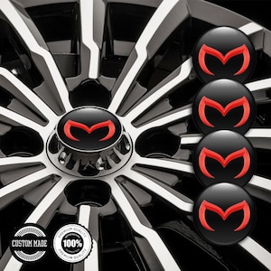 Puede incluir: Llanta de coche negra y cromada con tapacubos central con logotipo rojo y negro. Se muestran cuatro tapacubos adicionales con logotipo. La llanta tiene un diseño de radios en blanco y negro. Incluye dos insignias redondas de garantía de calidad.