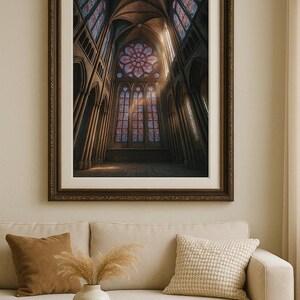 May include: A framed print of a cathedral interior with stained glass windows. The artwork features a rose window and arched ceilings, with light streaming through the windows. The frame is dark brown.