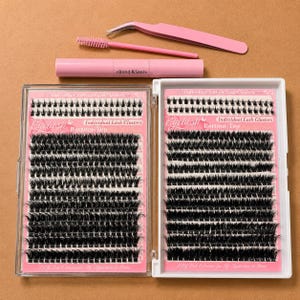 May include: A set of individual black eyelash clusters in two clear plastic cases, accompanied by a pink applicator tool, a pink spoolie brush, and a pink tube labeled Bond & Seal. The lash trays feature rows of lashes with printed text.