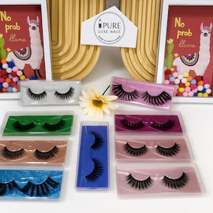 May include: Selection of false eyelashes in various colours, including green, blue, and pink. The image also features framed artwork with a llama and the text "No prob llama."