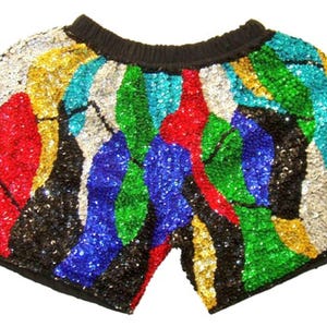 May include: Sequin shorts with a black elasticated waistband. The shorts are covered in colourful sequins in a patchwork design of red, blue, green, gold, silver, and black. A fun and festive garment.