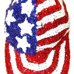 May include: A baseball cap completely covered in red, white, and blue sequins arranged in the pattern of the American flag. The front panel features a blue field with white stars, while the rest of the cap and the brim display red and white stripes.